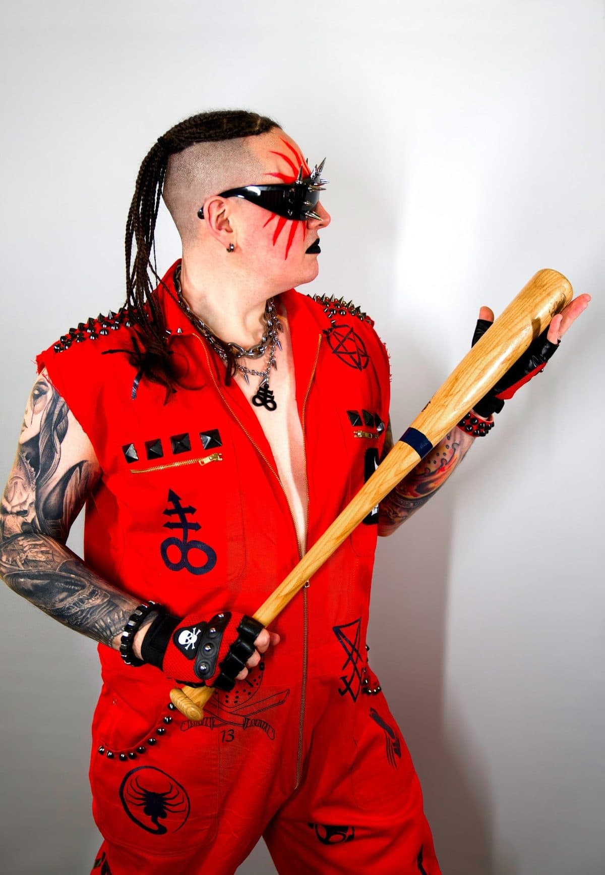 Rapha Hell in a red jumpsuit with a baseball bat