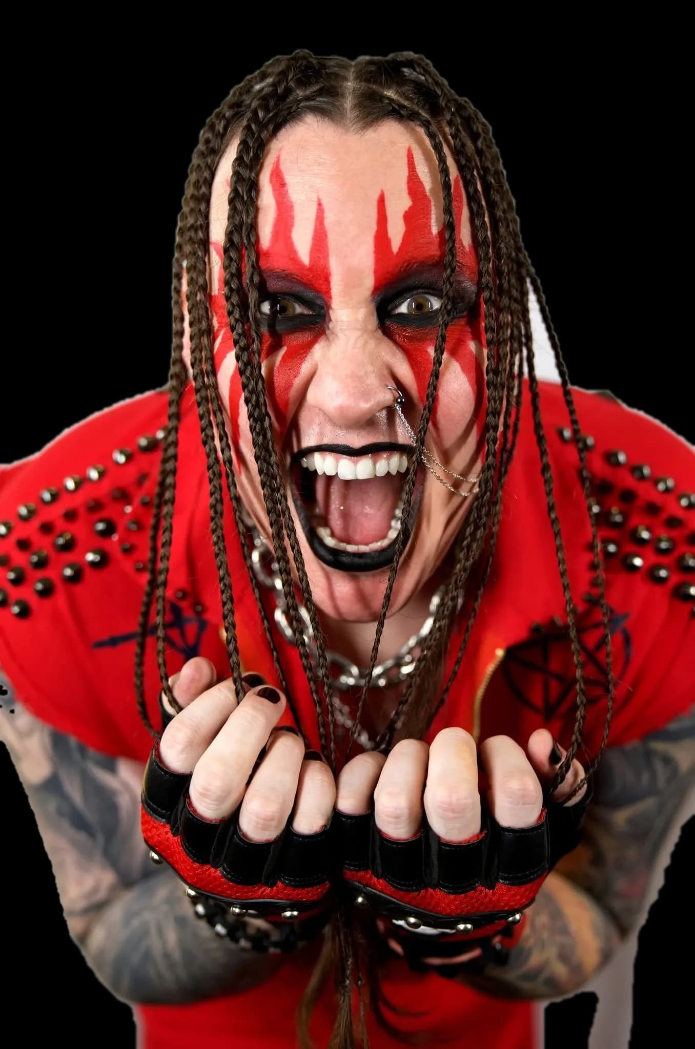 Rapha Hell of EXTIZE screaming, fists forward, in red flame face paint and a studded red jacket